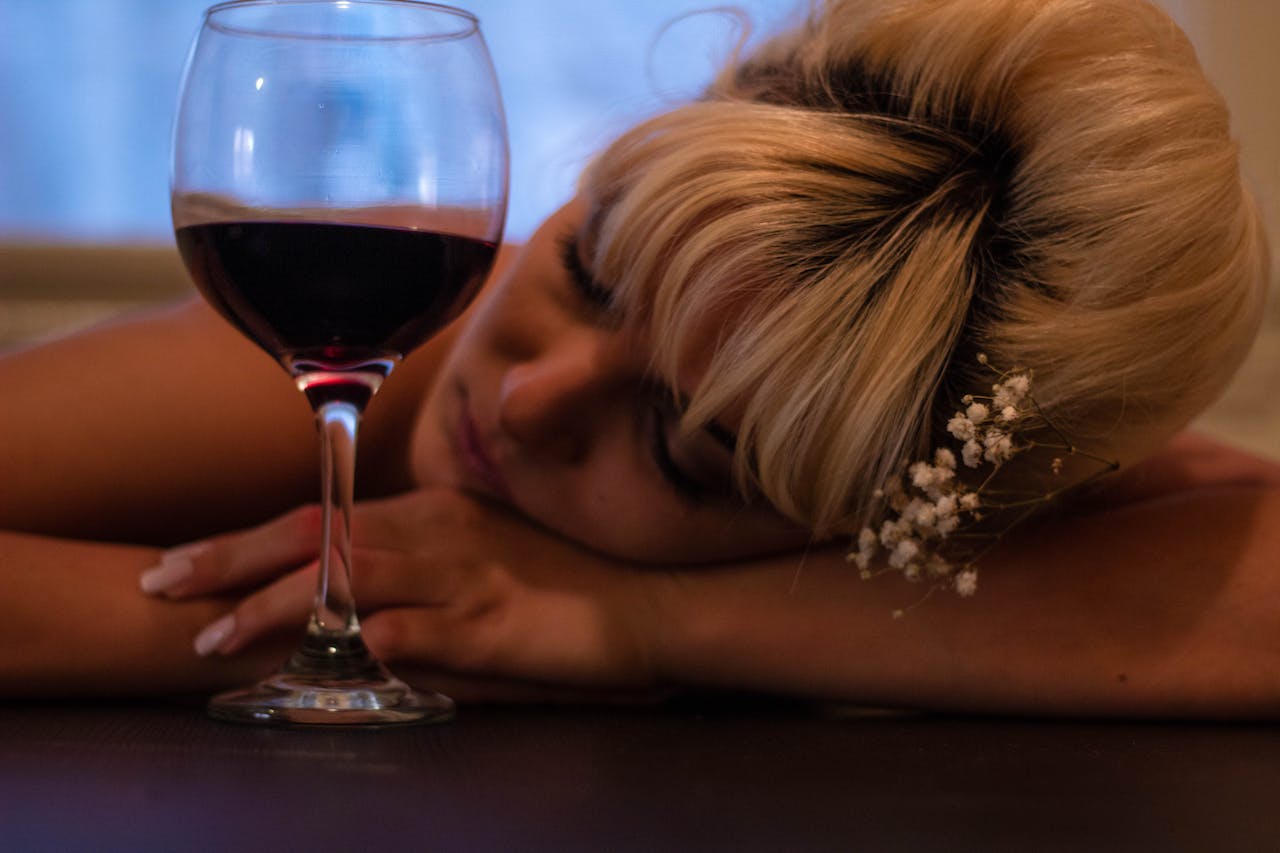 A woman with her hand on her hand and a glass of wine next to her representing community resources for alcohol addiction recovery in Pennsylvania