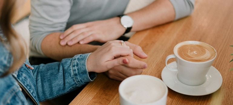 A happy couple holding hands while having coffee. 