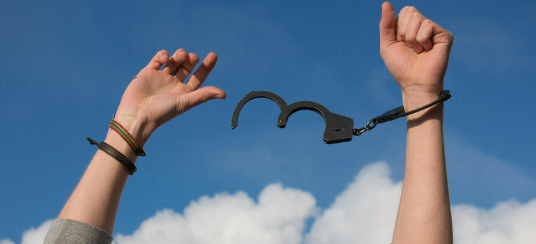 hands with open handcuffs against the blue sky representing feeling free