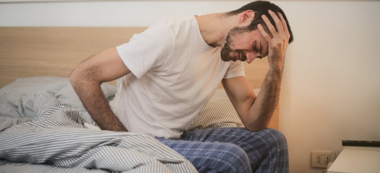a man leaning his head on his hand in bed
