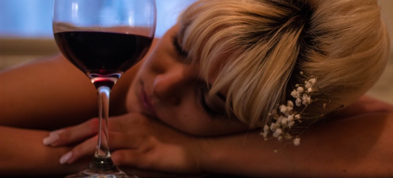 a woman sleeping on the table next to a glass of wine after mixing benzos and alcohol 