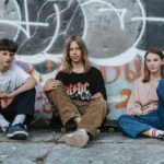 three teens sitting on the pavement
