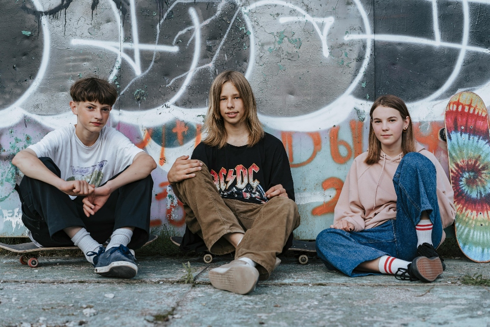 three teens sitting on the pavement