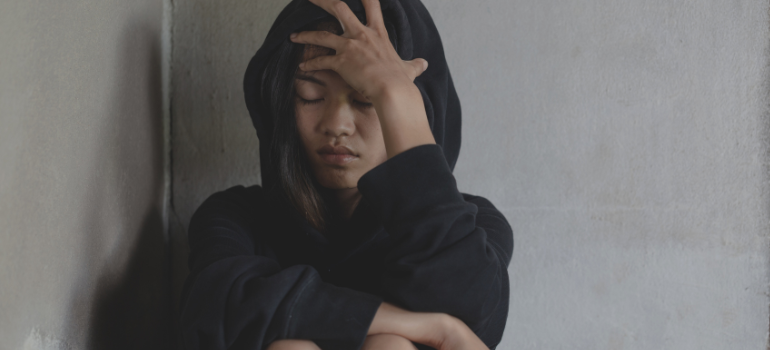 A feminine presenting person in a black hoodie going through methadone withdrawal symptoms