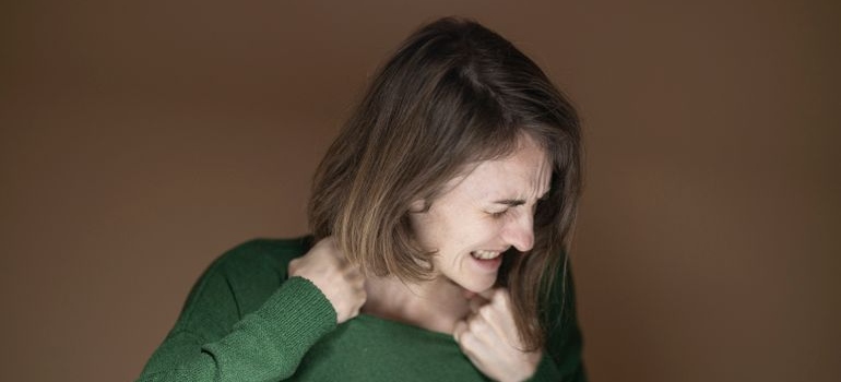 Angry woman grabbing the collar of her sweater.