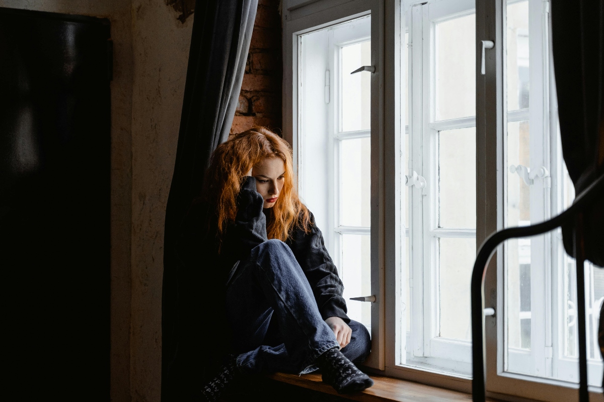 a young woman sitting near the window, exhibiting the signs of heroin use