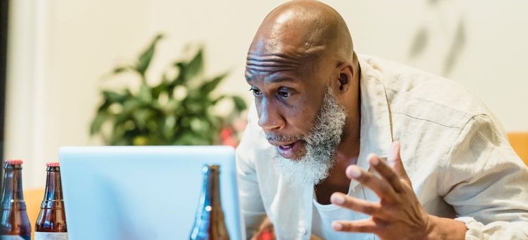 Man dealing with anger and addiction while yelling at his laptop.