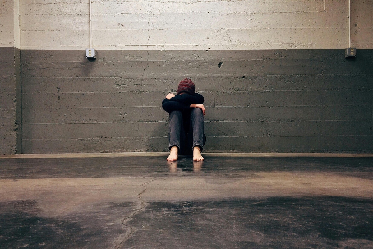 a person sitting against the wall with the head on the knees