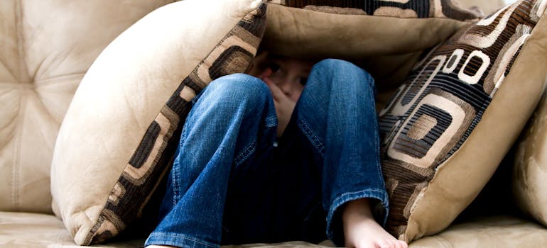 a child hiding among the cushions on the sofa