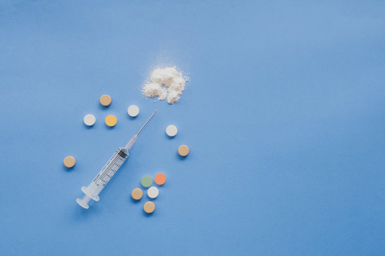 a syringe and pills on a blue surface