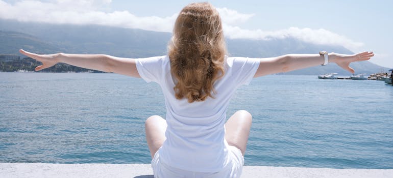 a woman meditating and looking at the sea
