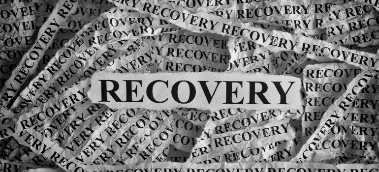 A bigger piece of paper with recovery printed on it is in the center among smaller pieces of paper that also say recovery