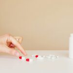 a person picking up a pill from the table