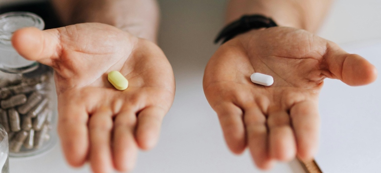 A person holding one yellow and one white pill