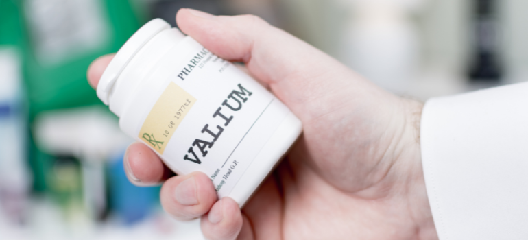 a person holding a bottle of Valium pills wondering does Valium Show Up on a Drug Test