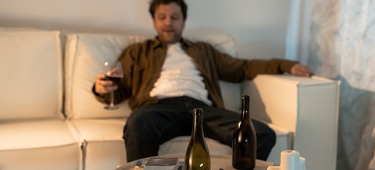 Man drinking wine while sitting on his couch.