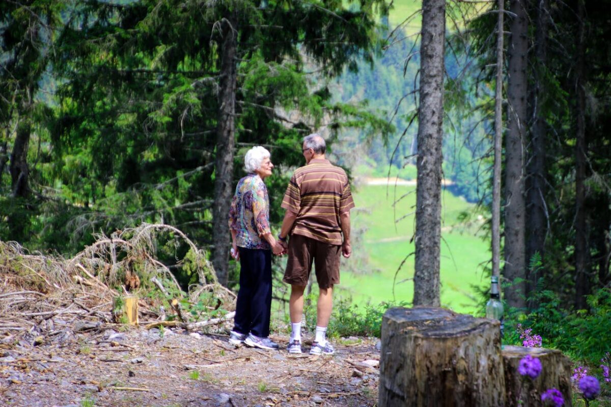 Two elderly people standing in a forest