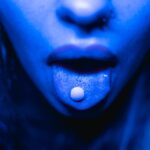 a woman with a pill on her tongue showing the designer drug problem