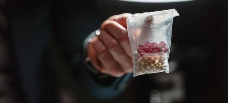 a man holding a bag of pills showing the The Designer Drug Problem
