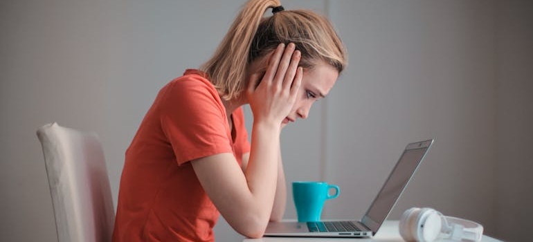 Woman looking at her laptop and holding her head.