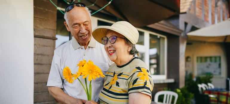 An elderly couple holding yellow flowers