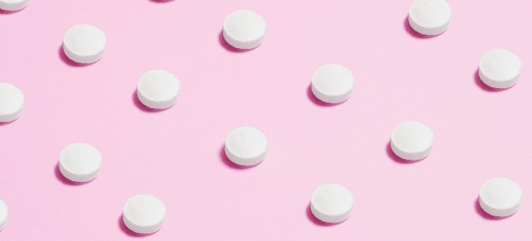 White pills on a pink background