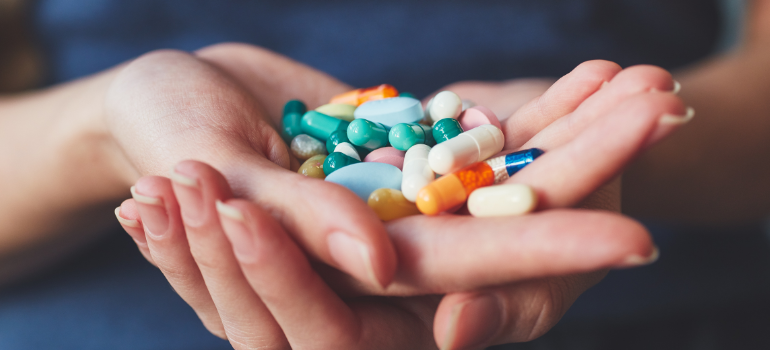 a person holding multi-colored pills wondering how long does methadone stay in your system