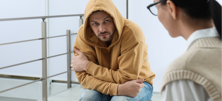 A young man looking troubled with a yellow hoodie and a young woman talking about how long does methadone stay in your system