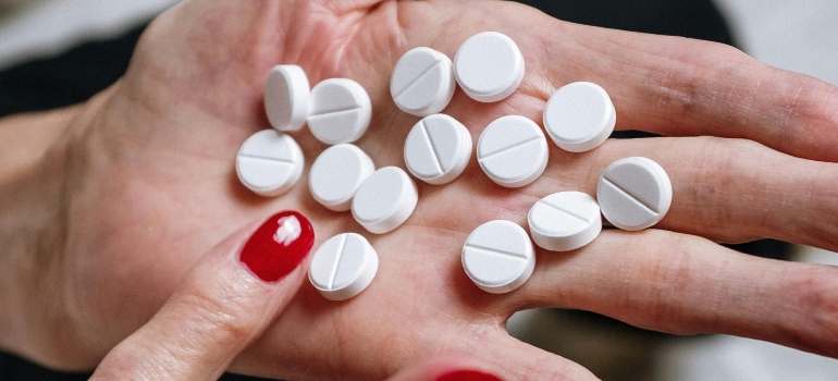 Woman counting pills on the palm of her hand.