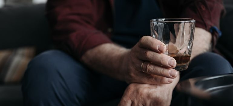Man holding a glass of whiskey while worrying about risks of mixing Gabapentin and Tramadol.