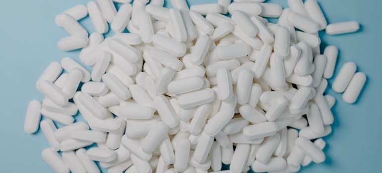 Numerous white pills on a blue background.