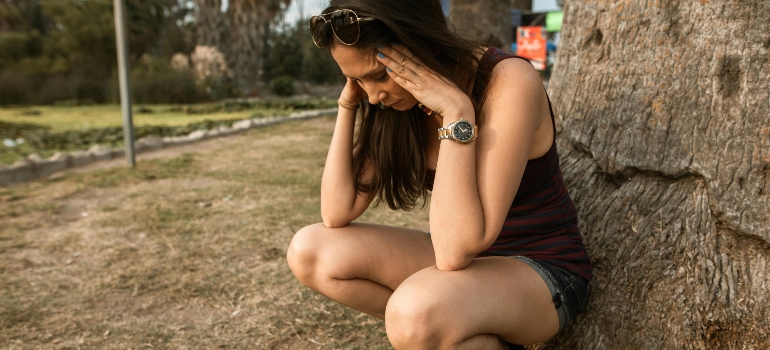 A woman is holding her hands on her head, feeling bad from Salvia drug.