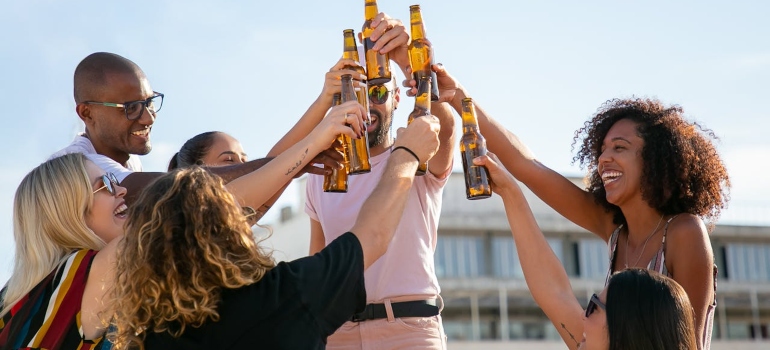 a group of friends cheering with bottles of beer