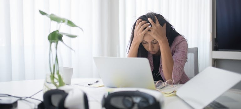 Woman looking at her laptop and holding her head.