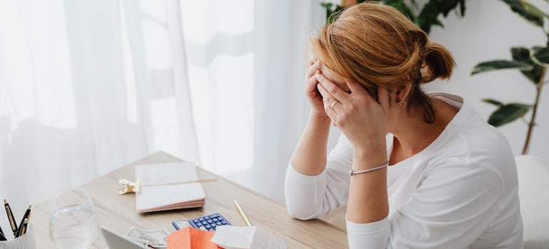 Woman covering her face while looking through her bills and wondering what addiction is the hardest to overcome