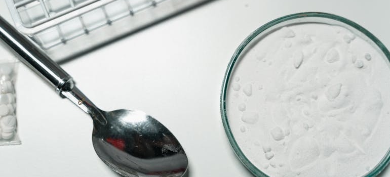 Spoon next to a container with white powder.