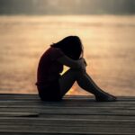 a sad person sitting near the water wondering if drug addicts ever change and find a path to recovery?