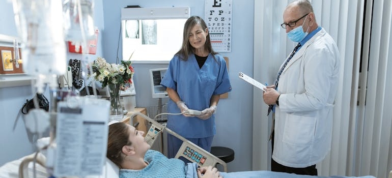 Surgeon and nurse talking to a patient who is lying in a hospital bed.