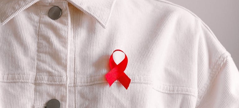 Person wearing a red ribbon on their jacket.