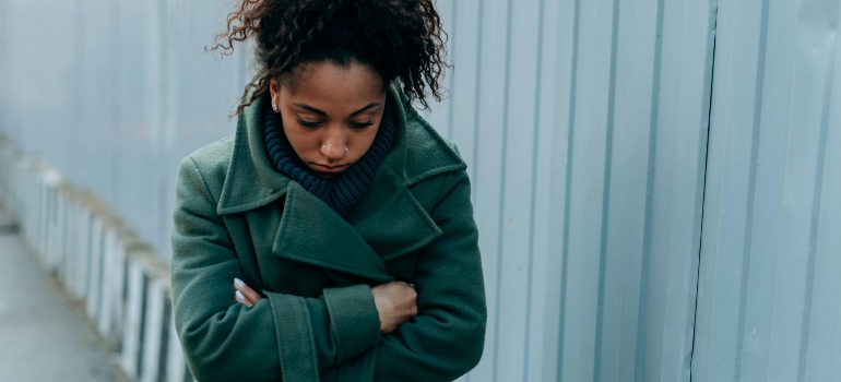 A depressed woman in the green jacket is walking outside and thinking about how to overcome Vyvanse addiction.