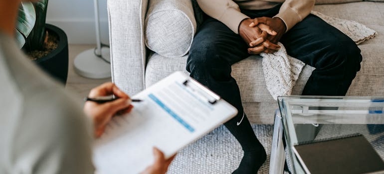 Psychologist writing on a clipboard while talking to a patient about speedball drug.