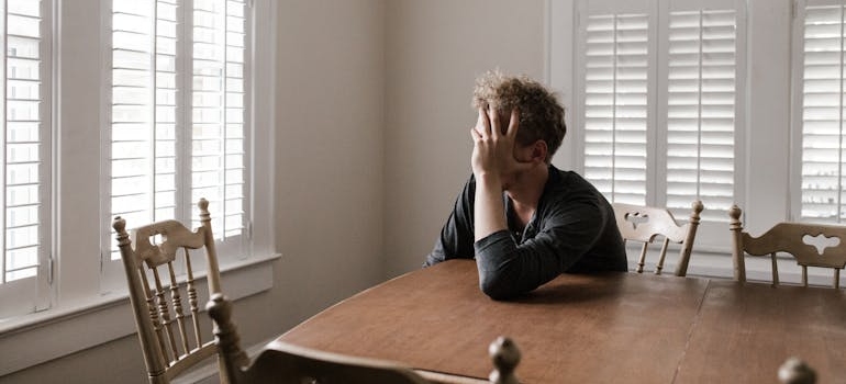 Man sitting on a chair and holding his head with his hand.