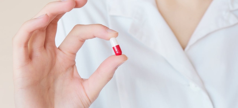 A doctor holding a pill as a symbol of prescription drug monitoring program 