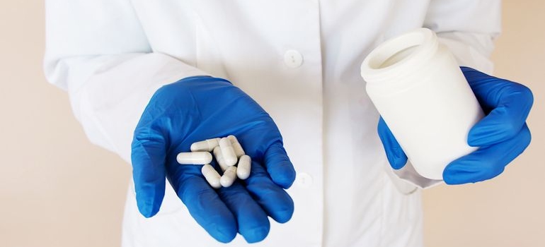 Medical professional holding prescription pills and a medication bottle.