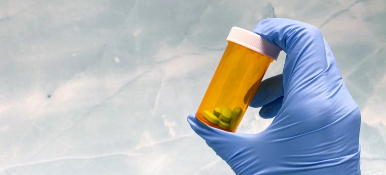 Prescription medication bottle held by a healthcare worker.