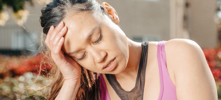 Woman holding her head while experiencing physical discomfort after ingesting pink cocaine.