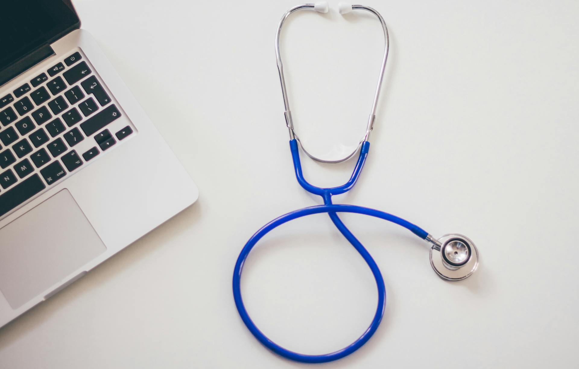 stethoscope and laptop on a white desk