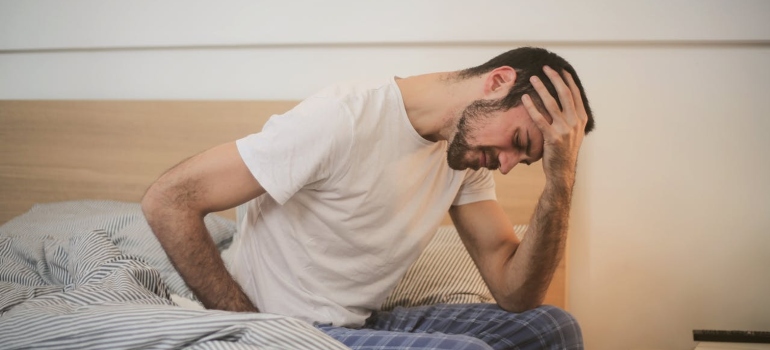 a man sitting on the bed, feeling bad 