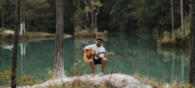 A man playing a guitar by the lake