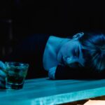 Woman lying on the bar and drinking a cocktail which means nobody recognized her addiction relapse warning signs